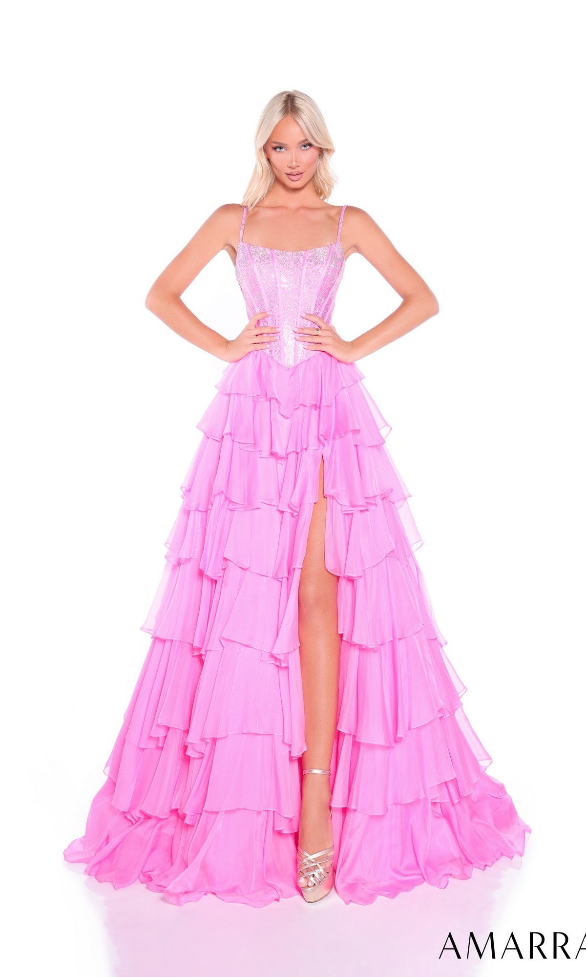 A woman poses against a white background wearing the Amarra 89459 Lace-Up Long Tiered Prom Dress in bright pink, featuring spaghetti straps and a thigh-high slit.